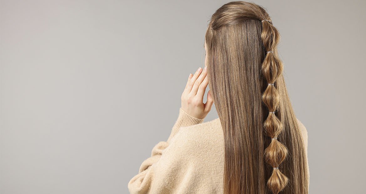 mulher branca de cabelo loiro escuro com cabelo meio preso com o penteado bubble braid